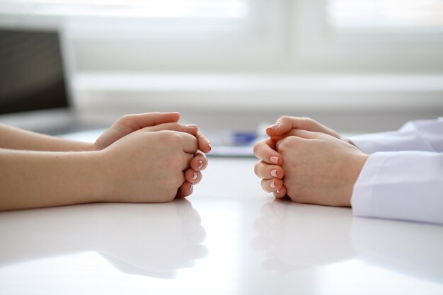 Arzt und Patient besprechen etwas nur Hände am Tisch