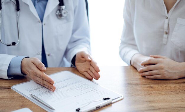 Arzt und Patient besprechen etwas, während sie nebeneinander am Holztisch in der Klinik sitzen, Blick von oben. Medizinkonzept.