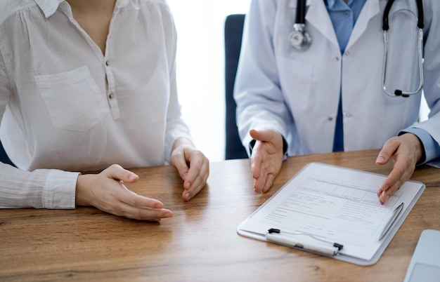 Arzt und Patient besprechen etwas, während sie nebeneinander am Holztisch in der Klinik sitzen, Blick von oben. Medizinkonzept