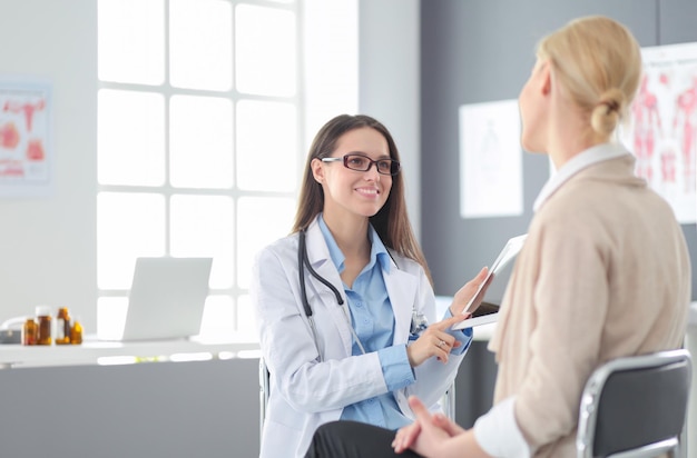 Arzt und Patient diskutieren etwas, während sie am Tisch sitzen Medizin- und Gesundheitskonzept