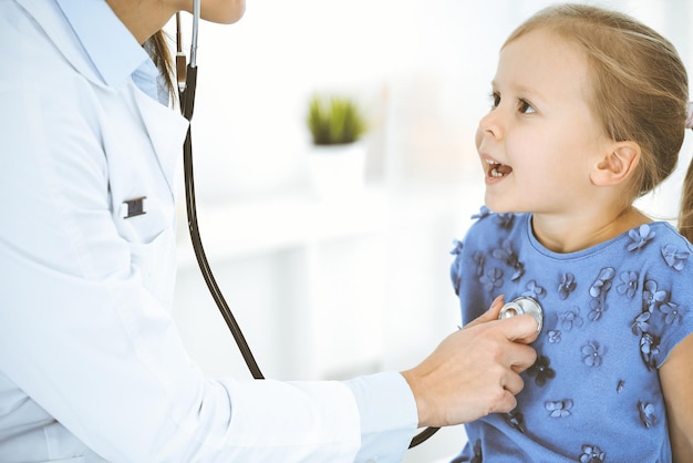 Arzt untersucht ein kleines Mädchen mit einem Stethoskop Glücklich lächelnder Kinderpatient bei der üblichen ärztlichen Untersuchung Medizin- und Gesundheitskonzepte