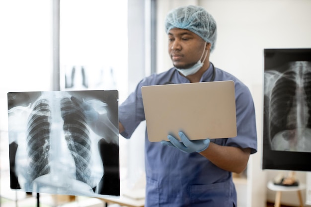 Arzt untersucht mit Laptop den Röntgenscan des Brustkorbs