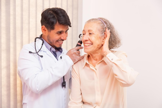 Arzt untersucht Ohr einer älteren Frau mit Otoskop in der Klinik