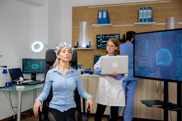 Arzt verfolgt Live-Daten auf einem Laptop während des Gehirnscans eines Mädchens. Headset zum Scannen von Gehirnwellen