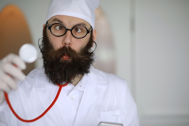 Foto arzt verrückt. ein verrückter bartwissenschaftler führt experimente in einem wissenschaftlichen labor durch. führt forschungen mit spritze und einem stethoskop durch.