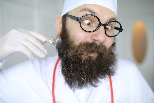 Arzt verrückt. Ein verrückter Bartwissenschaftler führt Experimente in einem wissenschaftlichen Labor durch. Führt Forschungen mit Spritze und einem Stethoskop durch.