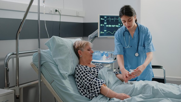 Arzthelferin setzt Oximeter auf Finger eines gealterten Patienten