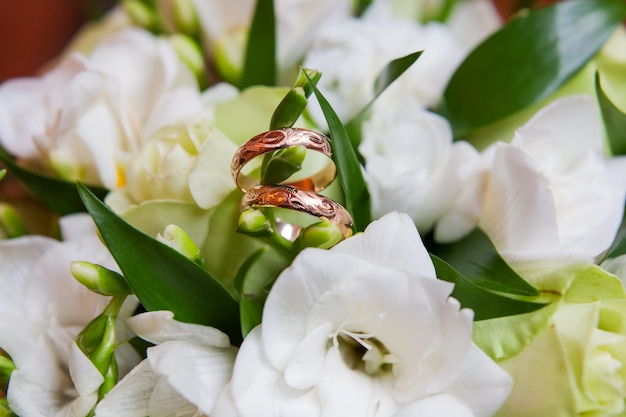 As alianças de casamento douradas com ornamento encontram-se dentro da flor no ramalhete.