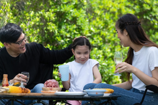 As atividades de férias em família incluem pai, mãe e filhos com churrasco de acampamento e brincar no quintal juntos alegremente nas férias