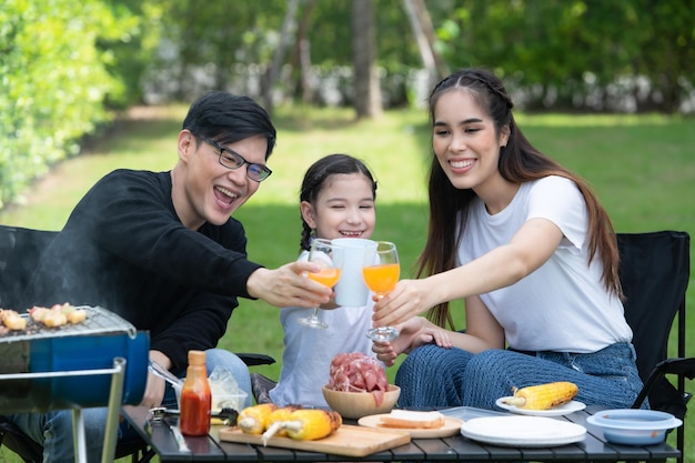 As atividades de férias em família incluem pai, mãe e filhos com churrasco de acampamento e brincar no quintal juntos alegremente nas férias