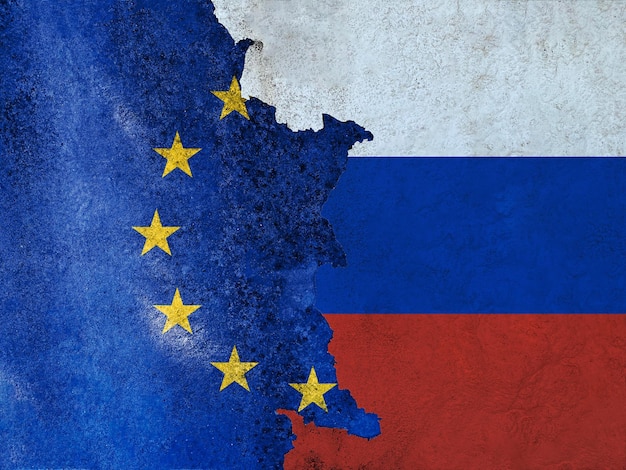 As bandeiras da União Europeia e da Rússia pintaram em uma parede arruinada e divididas por uma fenda diagonal Relações diplomáticas internacionais Estrutura danificada