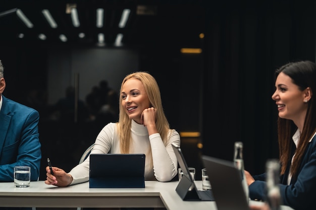 As belas empresárias sentadas à mesa na conferência de negócios