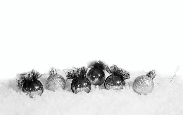 Foto as bolas de natal são prateadas e pretas e neve sobre um fundo branco sólido o conceito de natal