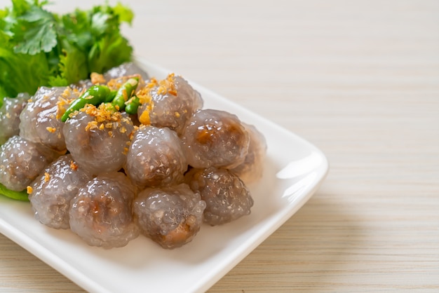 As bolas transparentes são chamadas de Saku Sai Moo ou Bola de Bolinhos de Tapioca Cozida no Vapor com Recheio de Carne de Porco