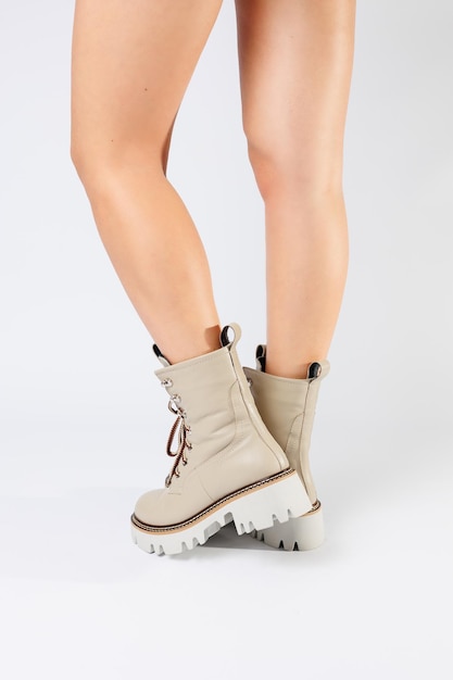 As botas de primavera brancas femininas feitas de couro genuíno são usadas na perna de uma mulher Nova coleção de botas femininas 2022