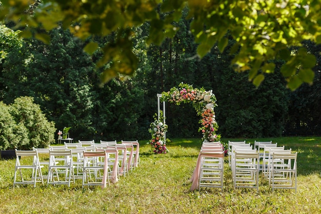 Foto as cadeiras de decoração de cerimônia de casamento espelham o ponteiro e muitas flores nas cores branca e rosa