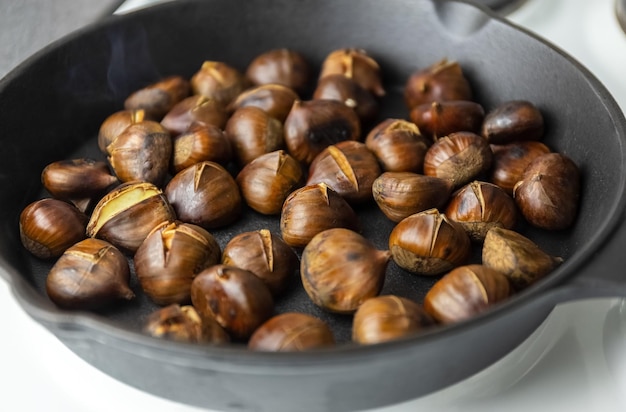 As castanhas maduras são fritas em uma frigideira. o processo de cozimento de castanhas. deliciosa iguaria. foto