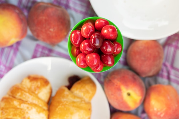 As cerejas são suculentas, brilhantes e doces em uma toalha de mesa de piquenique