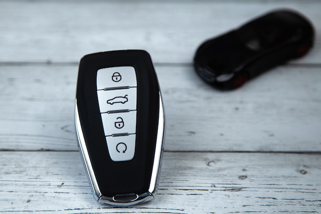 Foto as chaves do carro são pretas com inserções metálicas e botões automáticos no fundo de madeira branca em