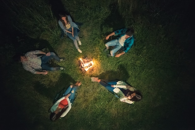 As cinco pessoas descansam perto da fogueira. vista de cima, noite, noite