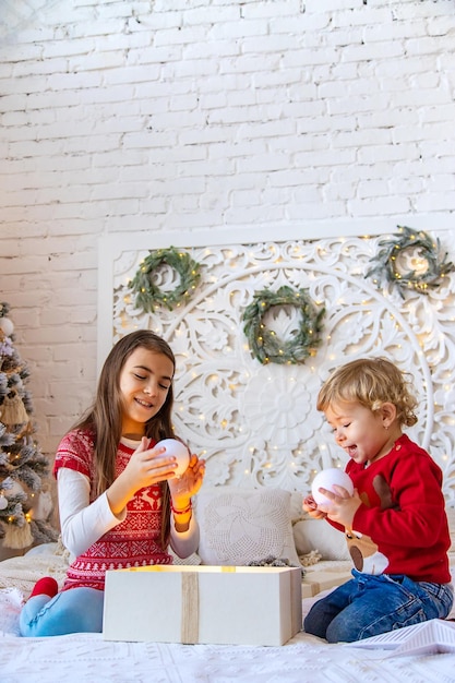 As crianças abrem presentes de Natal debaixo da árvore Foco seletivo