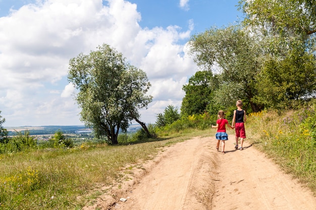 As crianças andam em uma estrada de terra