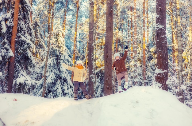 As crianças andam em uma floresta nevada de inverno