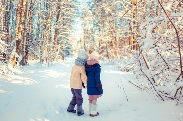 Foto as crianças andam em uma floresta nevada de inverno