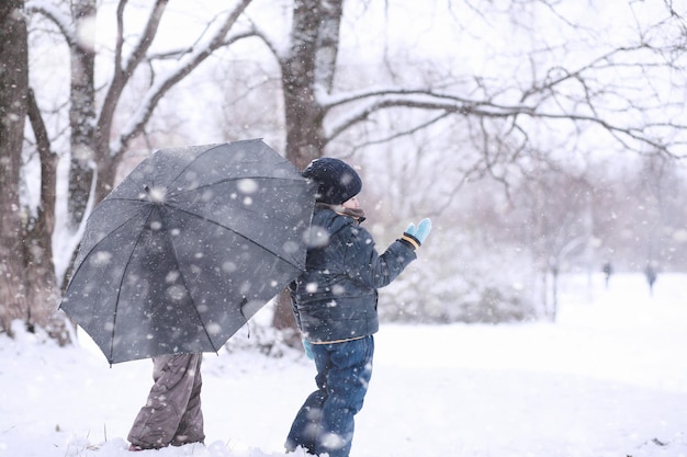 As crianças andam na primeira neve do parque