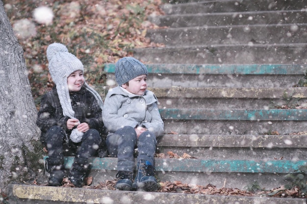 As crianças andam na primeira neve do parque