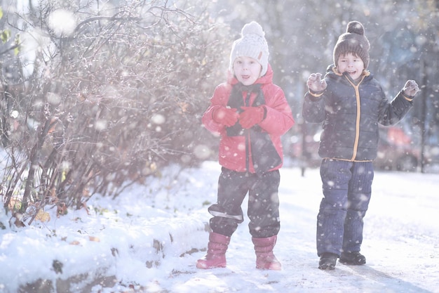 As crianças andam na primeira neve do parque