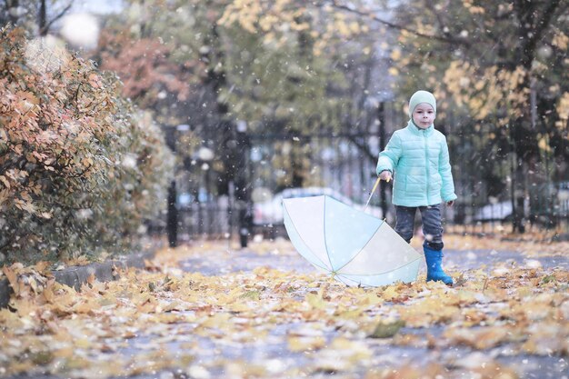 As crianças andam na primeira neve do parque