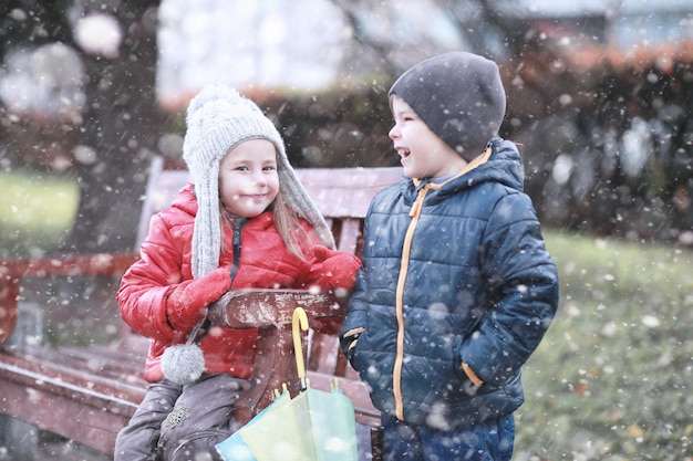 As crianças andam na primeira neve do parque