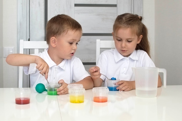 As crianças aprendem a misturar cores diferentes com água e tinta. Desenvolvimento precoce. Experimentos ou observações químicas e científicas. . O conceito de ciência da educação. Foco seletivo.