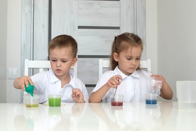 As crianças aprendem a misturar cores diferentes com água e tinta. Desenvolvimento precoce. Experimentos ou observações químicas e científicas. . O conceito de ciência da educação. Foco seletivo.