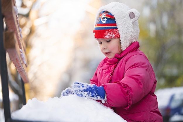 As crianças brincam com bolas de neve no inverno vestidas com casacos quentes