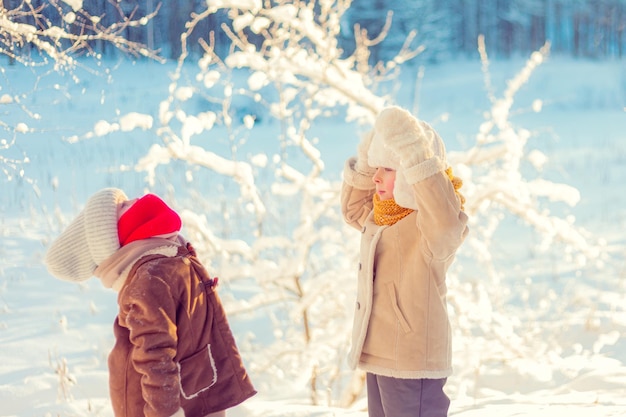 As crianças brincam em uma floresta nevada de inverno