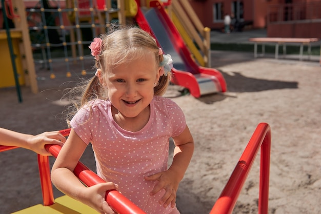 As crianças brincam no parque infantil. menino e menina rindo felizes se divertem balançando e escalando. atividade ao ar livre