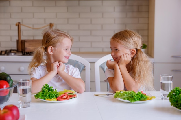 As crianças comem comida saudável na cozinha