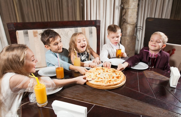 As crianças comem pizza em um restaurante.