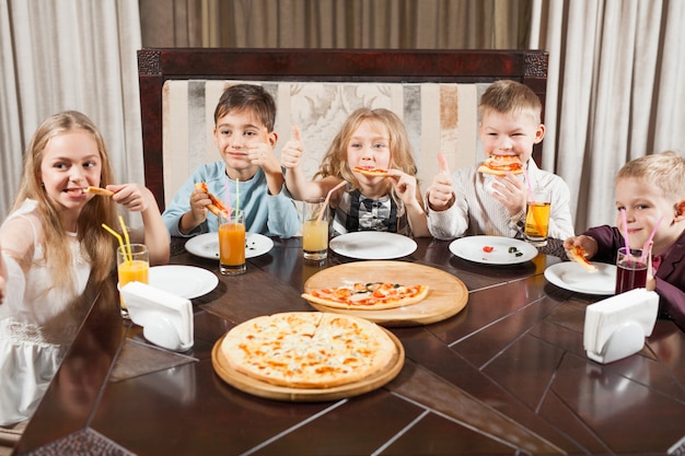 As crianças comem pizza em um restaurante.