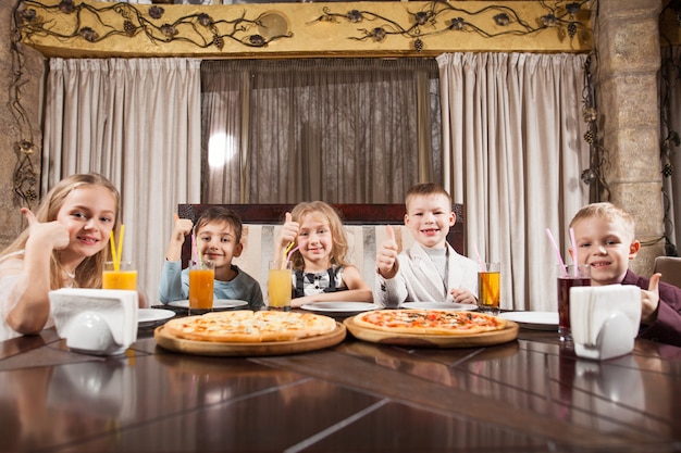 As crianças comem pizza em um restaurante.