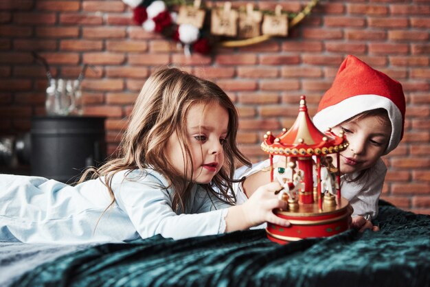 As crianças estão brincando com o carrossel de brinquedos na época do ano novo. uma garota está com chapéu de papai noel na cabeça.