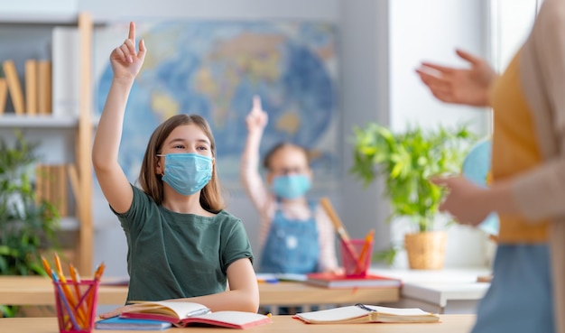 As crianças estão usando máscaras aprendendo na aula