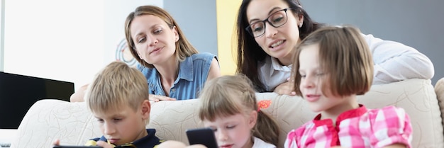 As crianças jogam jogos online em telefones celulares e as mães controlam assisti-los