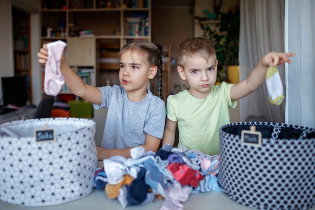 As crianças limpam o quarto, separam as meias e as arrumam em cestas pessoais. Rotina do dia a dia com diversão