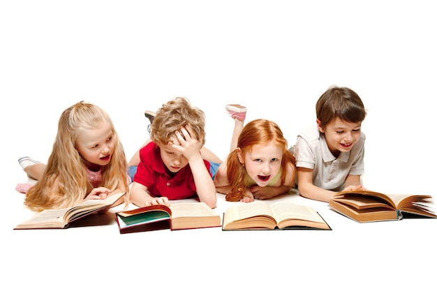 As crianças menino e meninas deitado com livros no estúdio, sorrindo, rindo, isolado no branco. Dia do livro, educação, escola, criança, conhecimento, infância, amizade, estudo e conceito de crianças