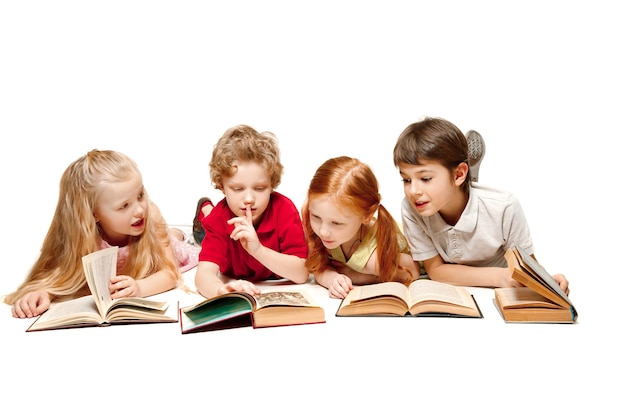 As crianças menino e meninas deitado com livros no estúdio, sorrindo, rindo, isolado no branco. Dia do livro, educação, escola, criança, conhecimento, infância, amizade, estudo e conceito de crianças