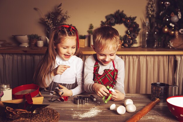 As crianças na cozinha estão preparando biscoitos. Decorações de Natal, tradições familiares, comida de Natal, vésperas de férias.