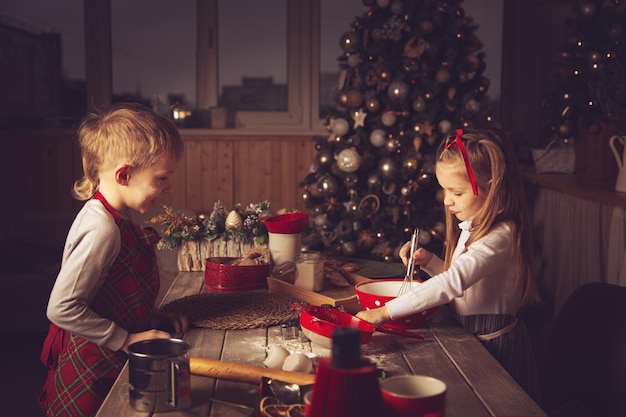 As crianças na cozinha estão preparando biscoitos. Decorações de Natal, tradições familiares, comida de Natal, vésperas de férias.